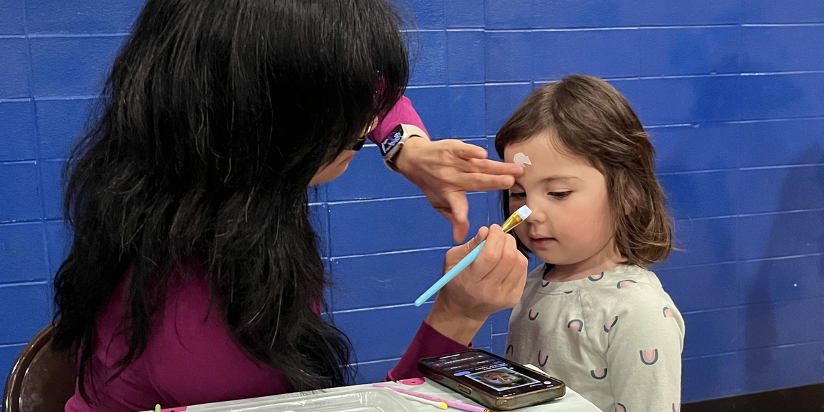 Parent volunteer paints faces at the NCAPO spring family dance